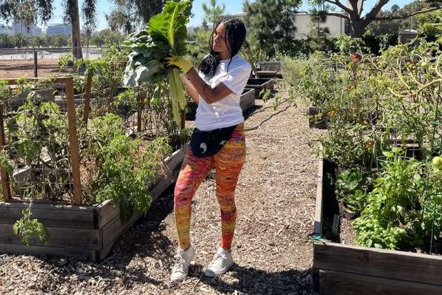 U.S. Air Force Veteran Cyntrea Cotton holds up produce at the Veteran's Garden where she volunteers.