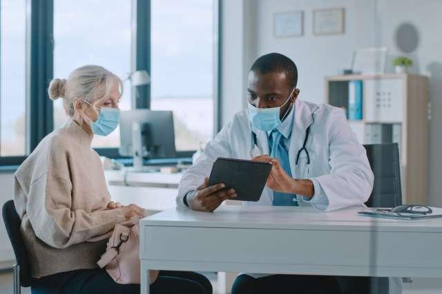 Physician Using Tablet Computer in Hospital Office.